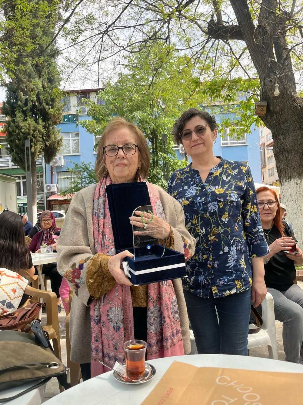 Resim 1:  Neriman Köylüoğlu plaketi ile “ Sn.Neriman Köylüoğlu; Hayatımızın Yönlenmesine Gösterdiğiniz Emek ve Katkılarınıza Teşekkür Ederiz- T.Ü. Külliyeliler”